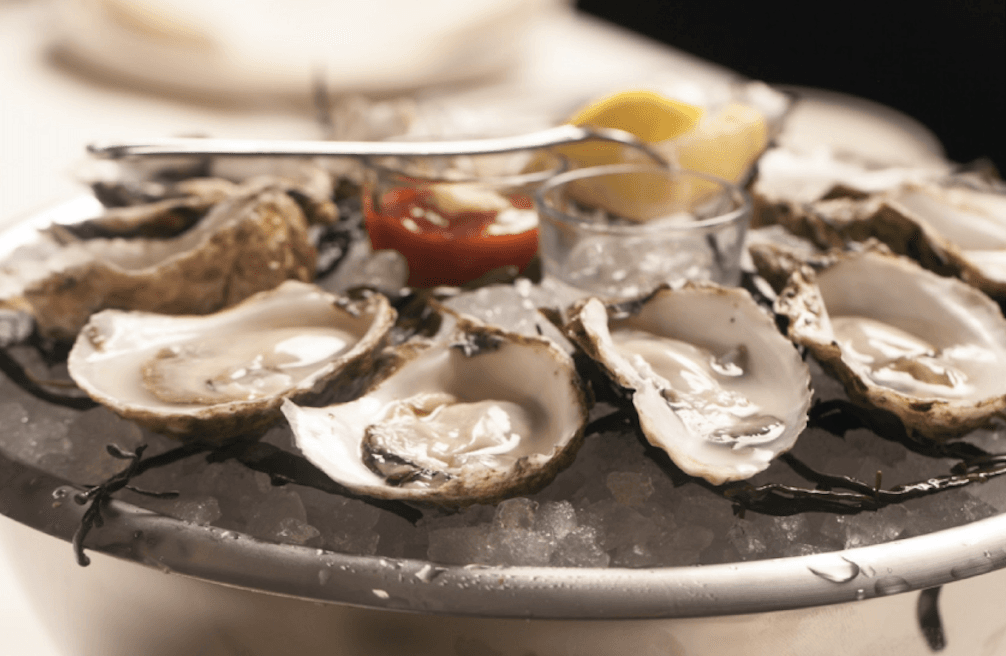 oysters on the half shell with cocktail sauce and a lemon